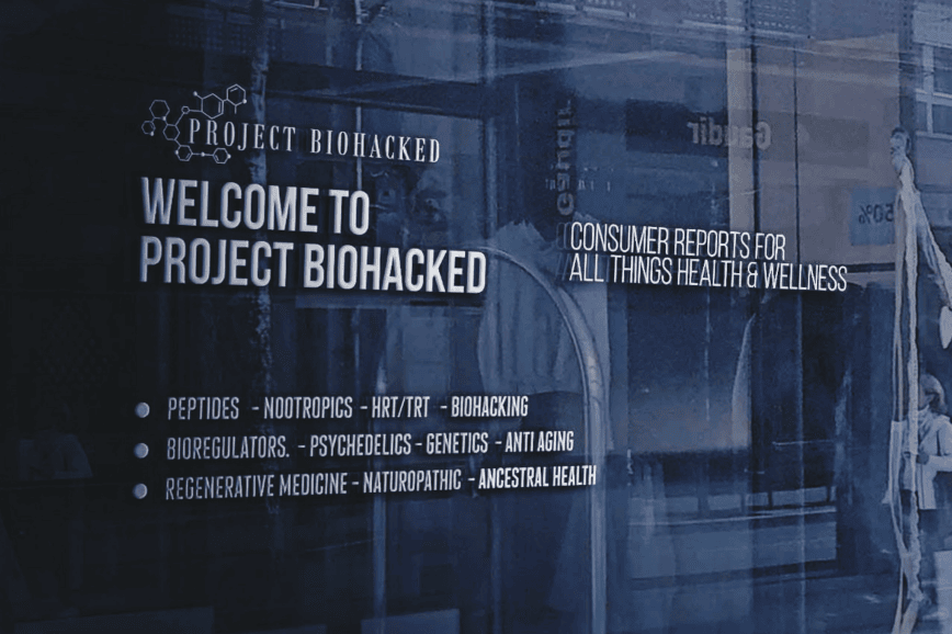 BPC157 Image 7 Sign on a glass window reads "Welcome to Project Biohacked" with topics like peptides, nootropics, HRT/TRT, psychedelics, and anti-aging listed underneath